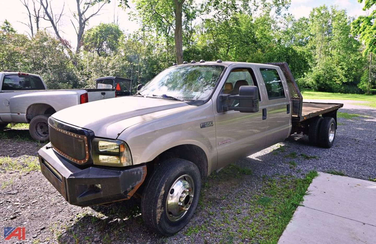 Ford F-550 stake bed truck shown in beige with dual rear wheels and flatbed.