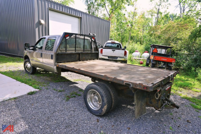 Ford F-550 stake bed truck in a yard with flatbed and dual rear wheels, VIN visible from listing context
