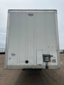 Rear view of a white 2016 Wabash van trailer with riveted aluminum panels. Small decals near lower left and a loading connection on the right.