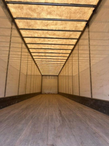 Interior of a Wabash van trailer showing a long empty cargo area with wooden floor and ribbed ceiling panels.