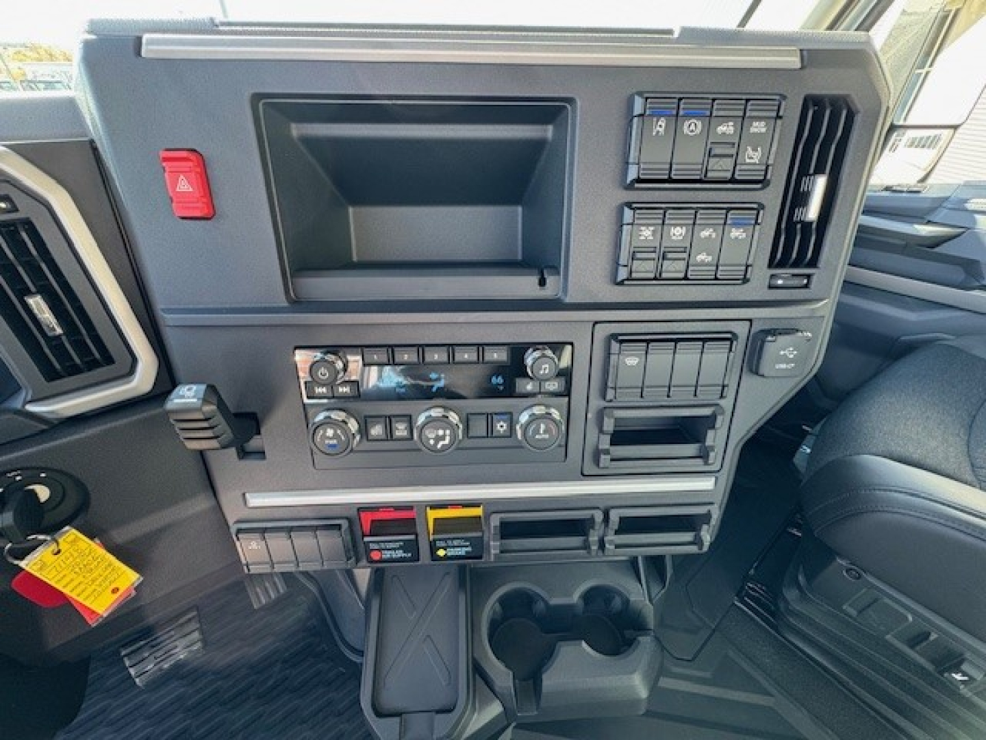Dashboard of a 2026 Mack PR64T truck showing control panel, vents, and storage compartments. Visible text on switches and controls but not engine data.