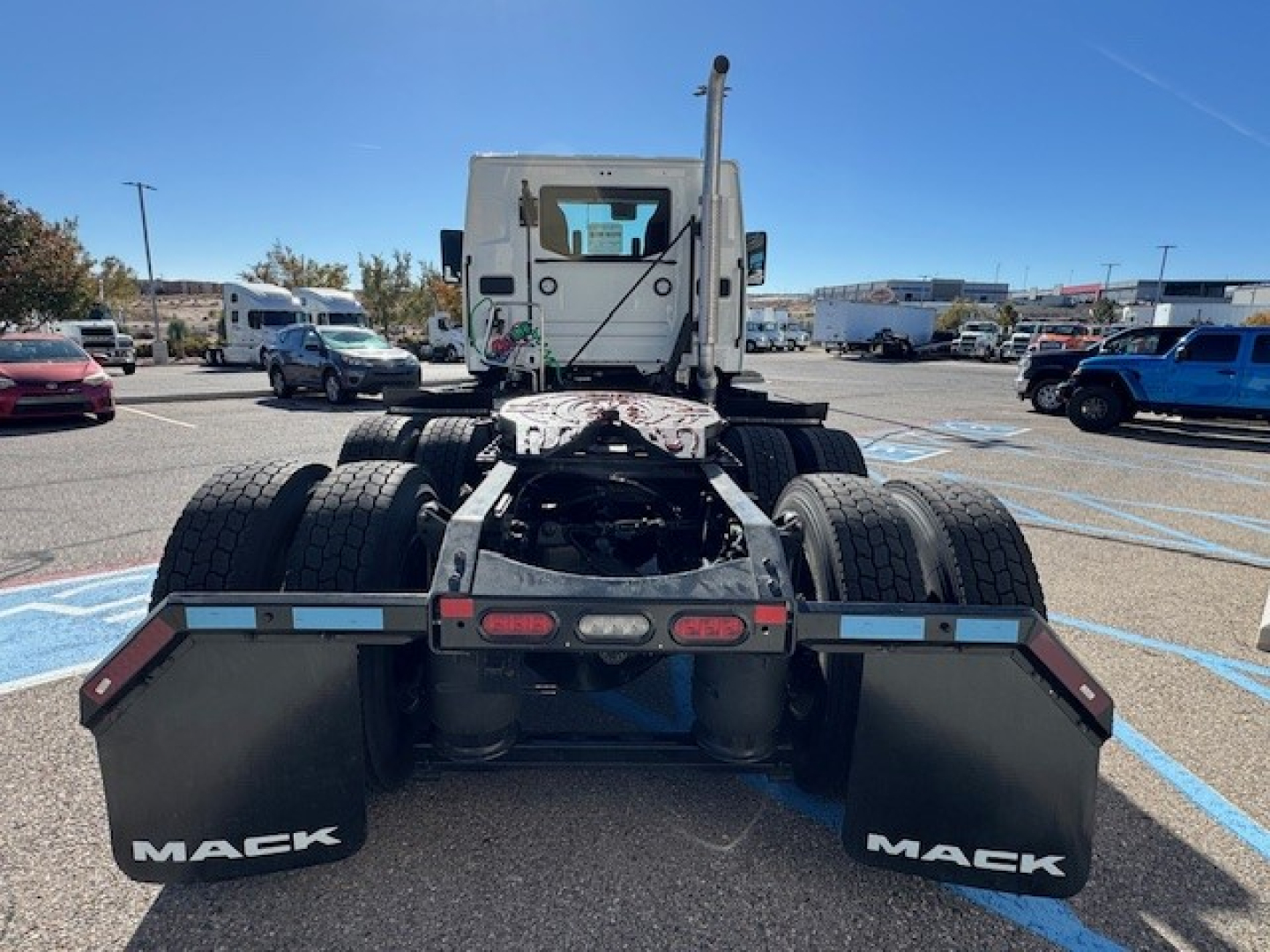 Truck chassis and rear view of a new 2026 Mack PR64T with fifth wheel and mudflaps labeled Mack, in a dealership lot
