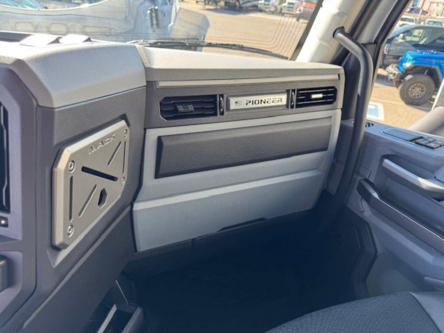 Pioneer dashboard badge on the Mack PR64T truck interior passenger side with stitched panels and vent, view from driver side door.