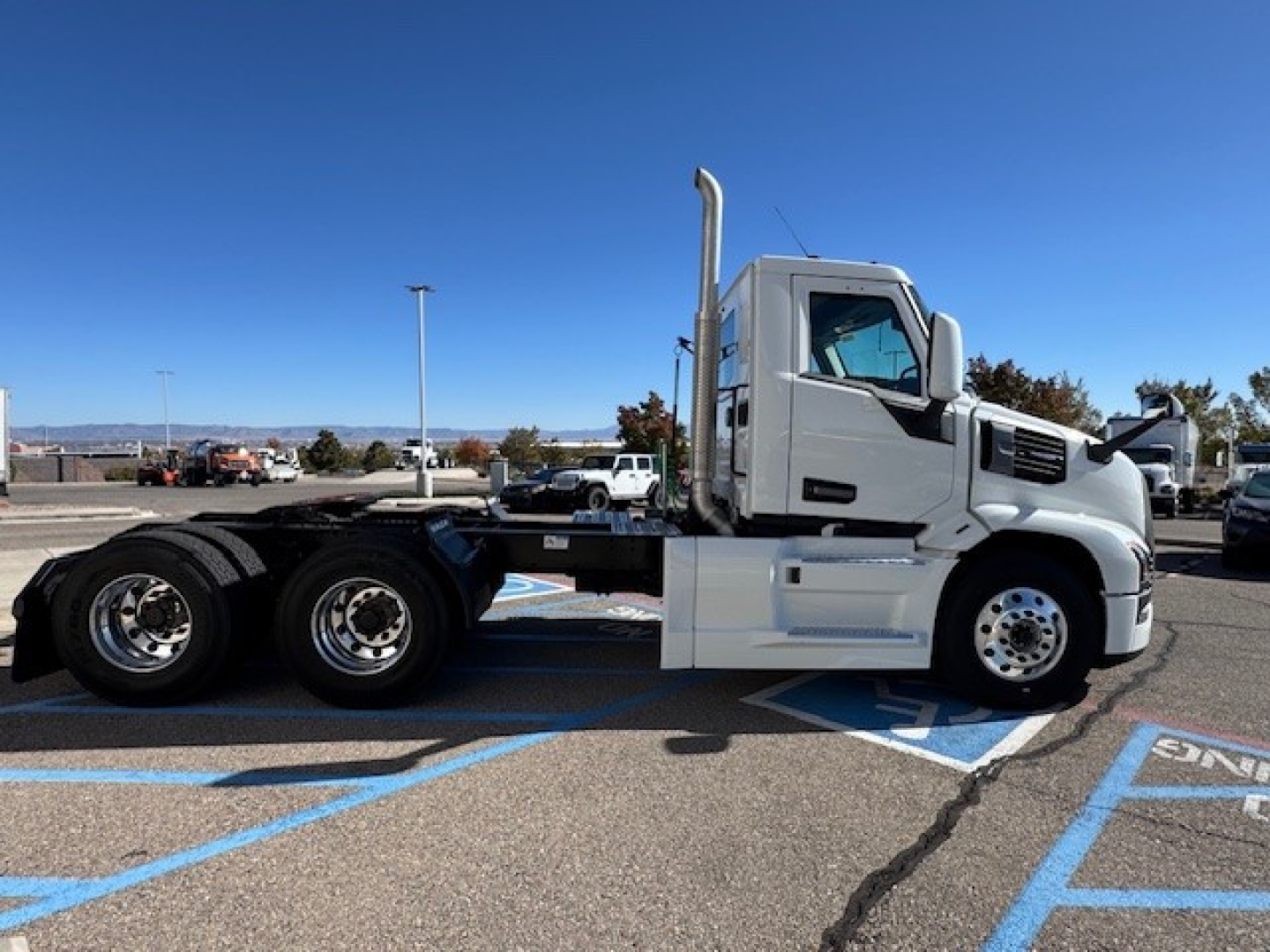 Road-ready Mack PR64T truck cab and chassis in profile view, showing large exhaust stack, sleeper cab, and dual rear axles in a parking lot.