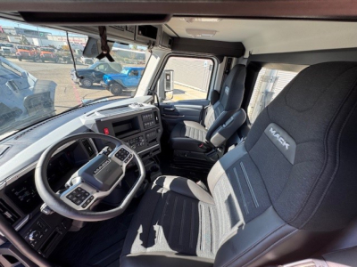 Cockpit of a 2026 Mack PR64T with steering wheel, dashboard, and driver seat visible from open cabin; modern controls and Mack branding on seat.