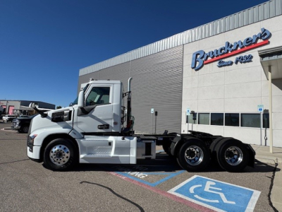 Mack PR64T conventional daycab tractor in front of dealership building with Brackner sign, side view showing cab, chassis, and dual rear axles.
