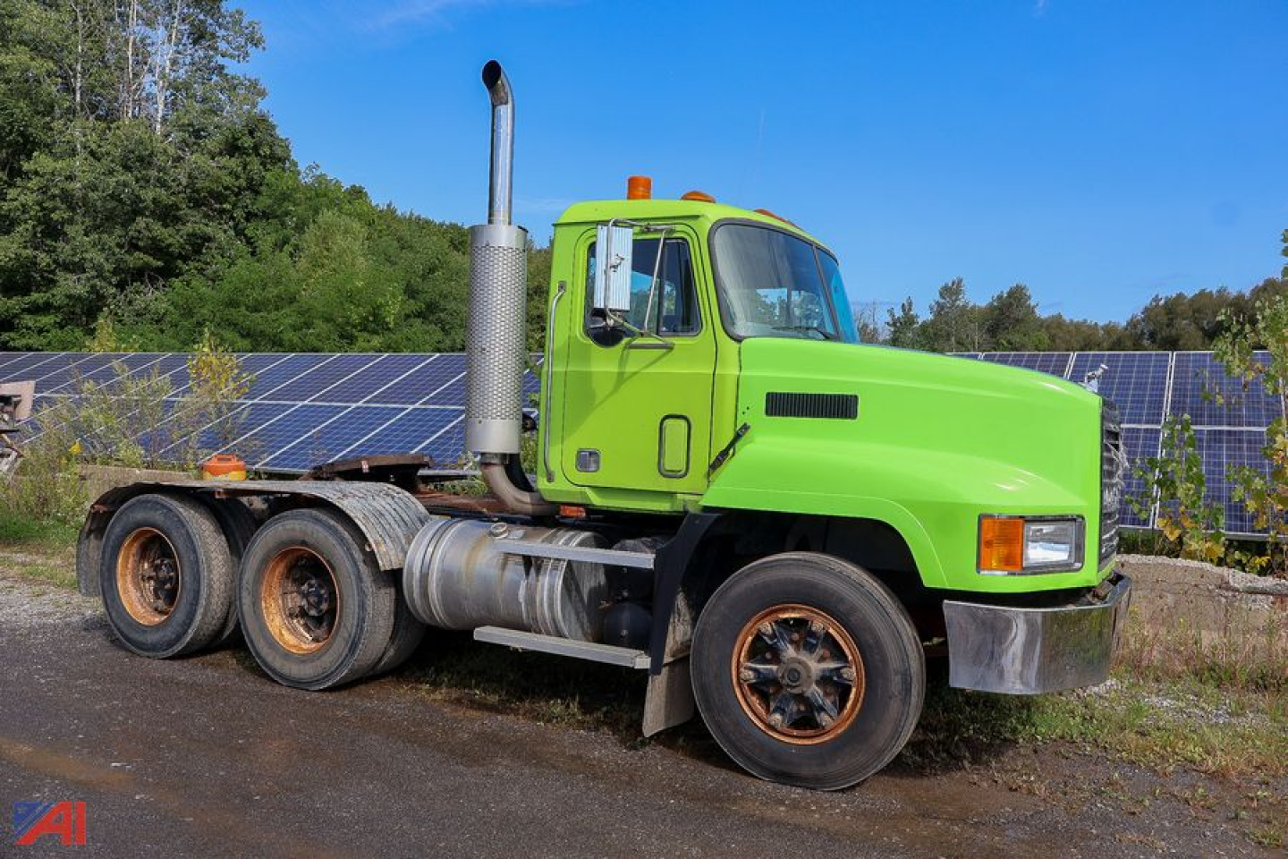 Green 1990 Mack CH613 tractor with three axles and tall exhaust stack, side view showing cab and fuel tanks.
