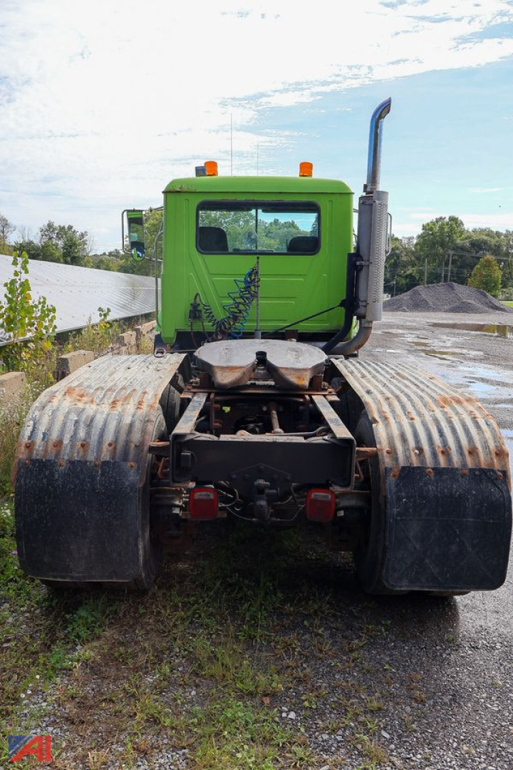 Mack CH613 tractor cab rear view showing green cab, large dual fuel tanks, and exposed chassis.