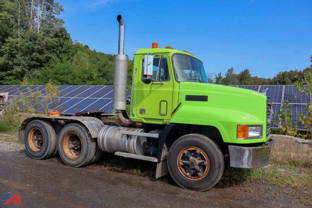 Green 1990 Mack CH613 tractor with three axles and tall exhaust stack, side view showing cab and fuel tanks.