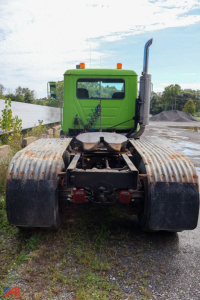 Mack CH613 tractor cab rear view showing green cab, large dual fuel tanks, and exposed chassis.