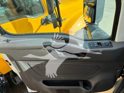 Truck cab interior door panel showing control switches and window with yellow truck outside.