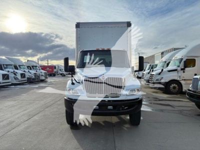 International MV box truck front view showing grille, headlights, and large cargo box with dealership lot in background.