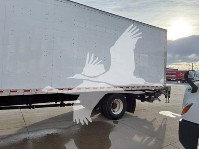 Truck trailer with a white silhouette of flying birds on the side; wheel and rear section visible in the cargo box truck.