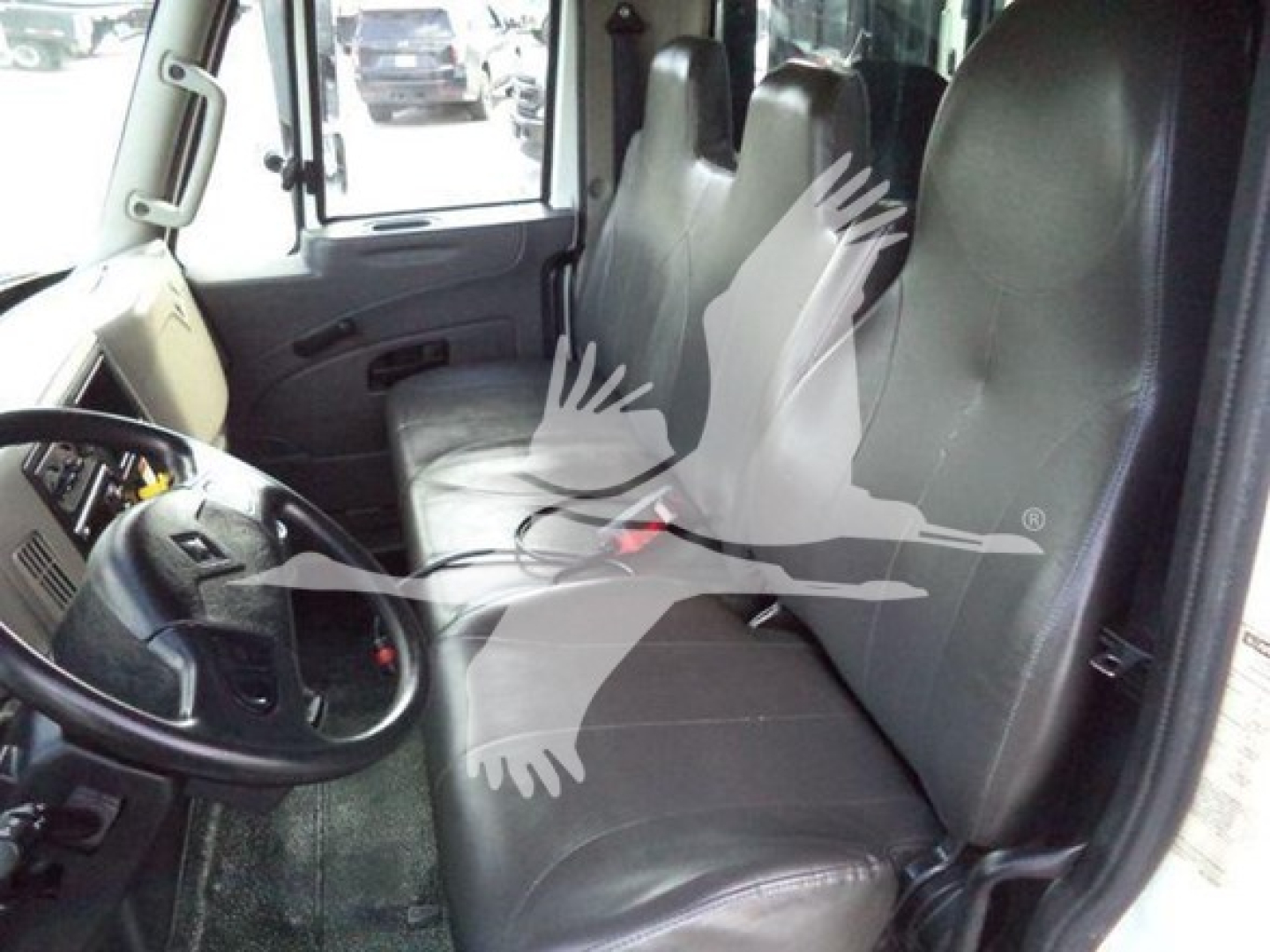 Truck cab interior showing front seat and two passenger seats with steering wheel and dashboard visible.