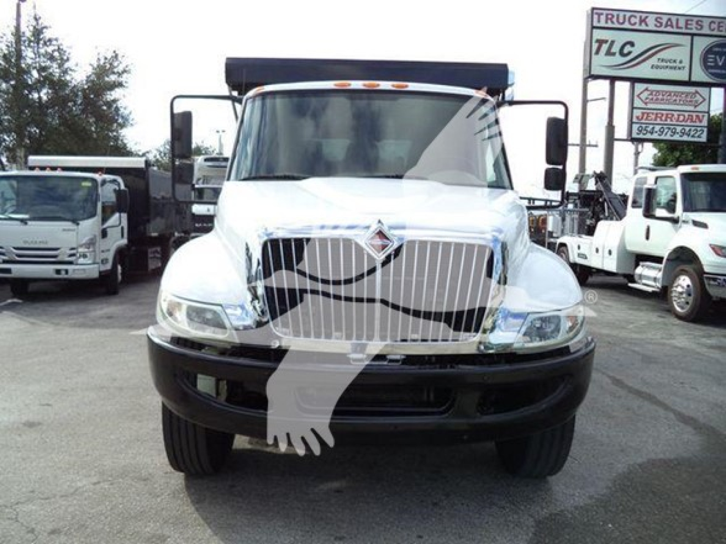Front view of a white 2019 International Durastar 4300 rolloff truck with large grille, headlights, and a black bumper. There is text on the right background sign and on the truck badges.