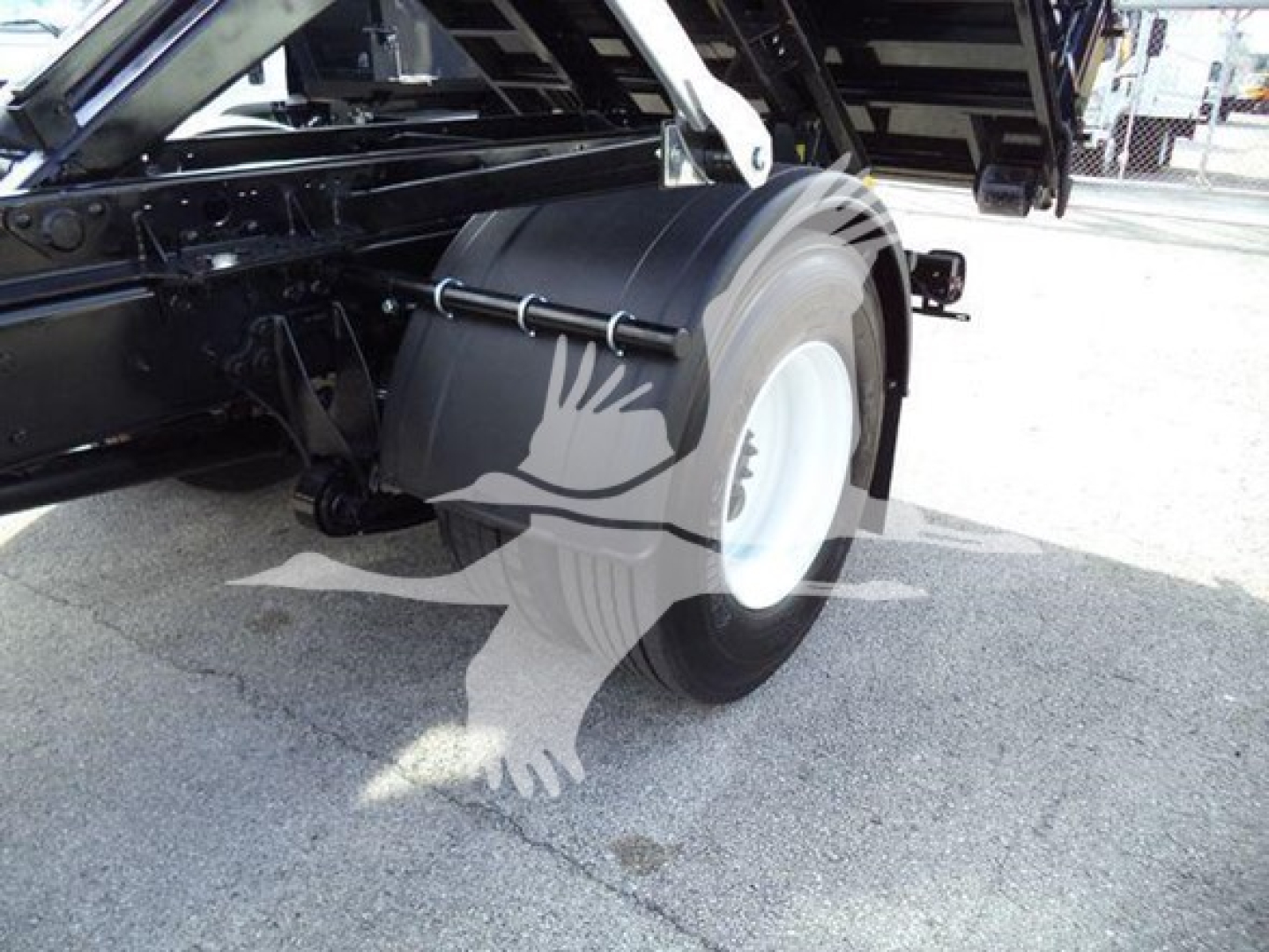 Truck rear wheel and roll-off body of a 2019 International Durastar 4300 showing spare tire, chassis components, and load bed area.