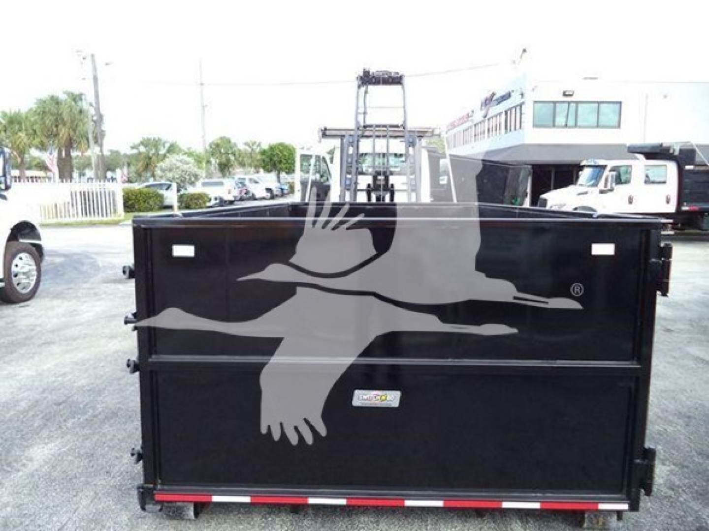 Truck body of a 2019 International Durastar 4300 roll-off with black metal dump bed showing a white logo of flying geese across the side.
