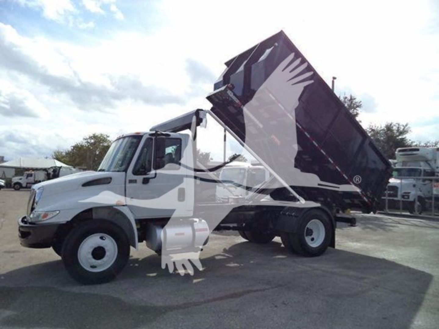 2019 International Durastar 4300 roll-off truck with dumped bed raised, side view shows cab and large dumping container.