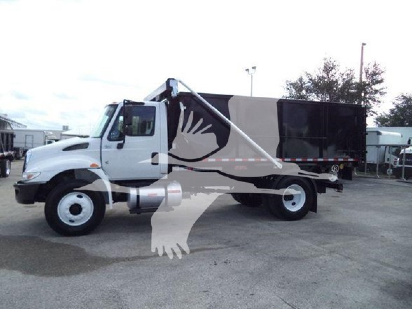 Truck side view showing a 2019 International Durastar 4300 roll-off with white cab and black dumping bed, VIN 1HTMMMML4KH515012, stock T15012.