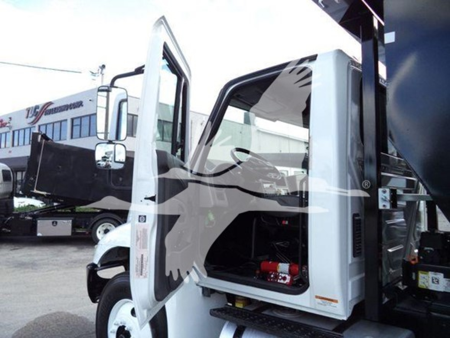 2019 International Durastar 4300 roll-off truck with cab doors open showing interior and equipment in the cargo area.
