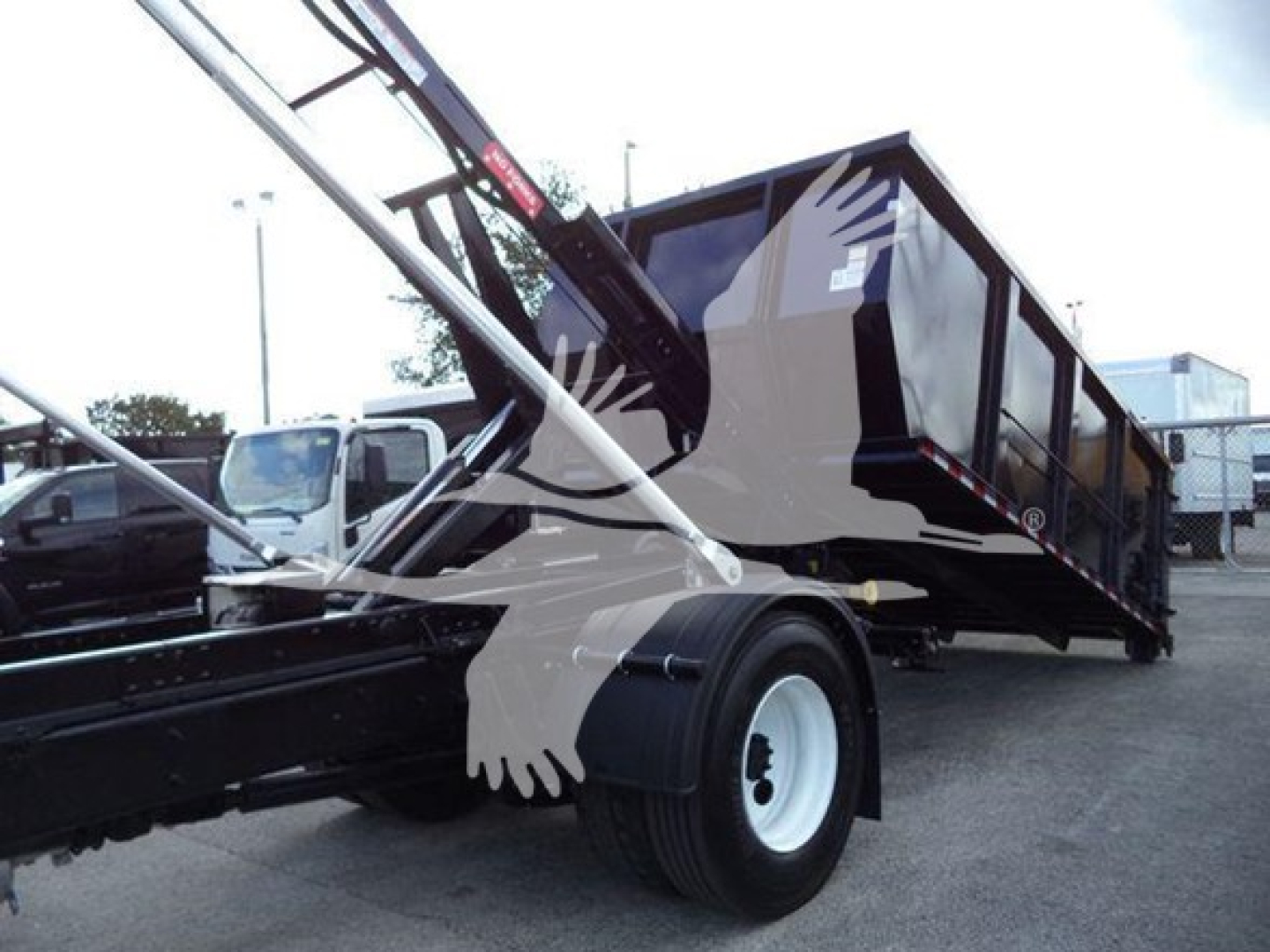 Truck wheel area and dumping trailer with hydraulic arm. Visible text includes no legible labels or stickers due to angle.