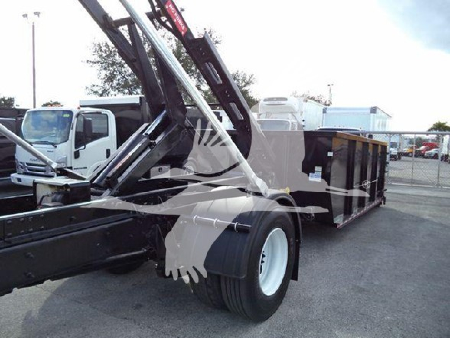 International Durastar 4300 roll-off truck showing hydraulic loader arms and long flatbed with white wheels.