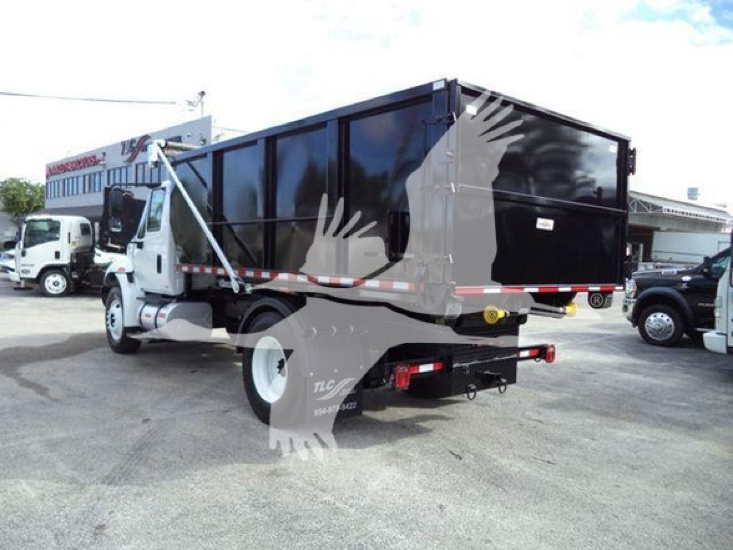 Truck body showing 2019 International Durastar 4300 rolloff with black dump box and white cab, side view.