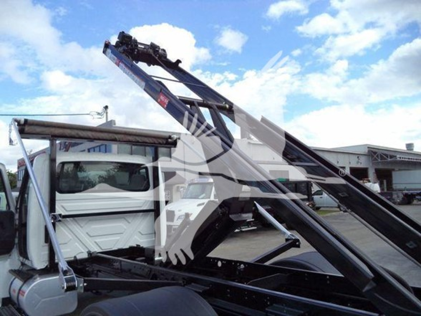 International Durastar 4300 roll-off truck with hydraulic lifting arm and cab, side view showing hoist mechanism.