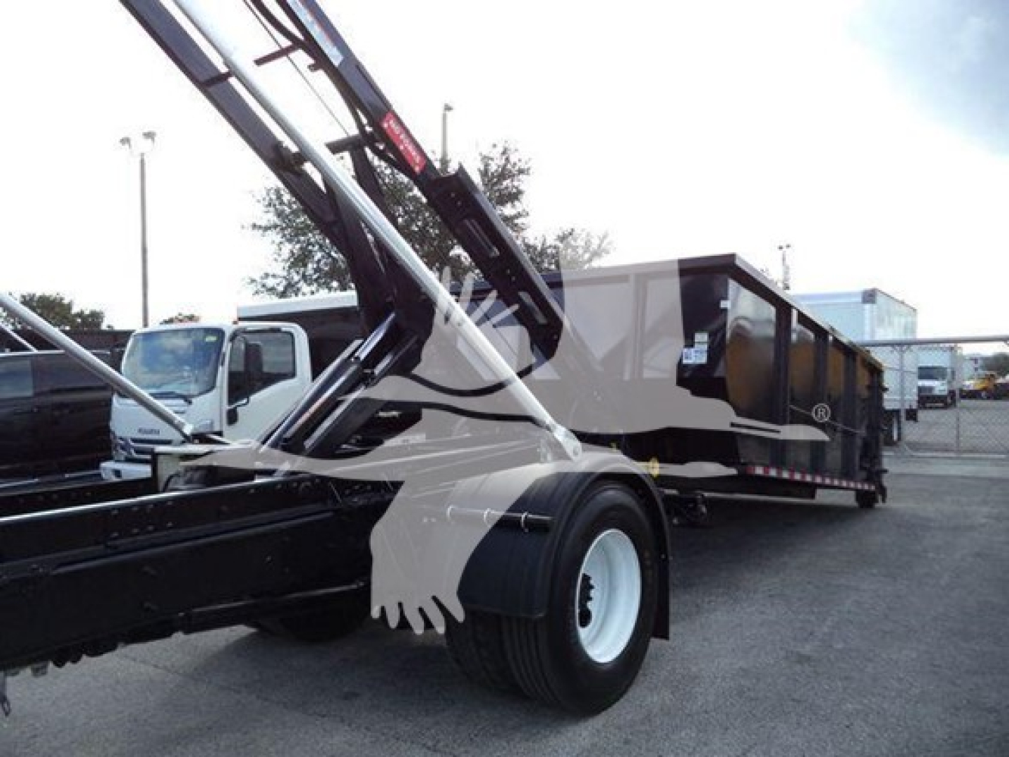 International Durastar 4300 roll-off truck in service with crane arm extended and a long black and gray dump body.