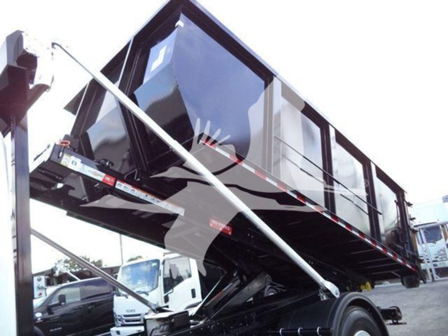 Dump body truck cab and chassis with roll-off dumpster in raised position showing side rails and hydraulic hoist components.
