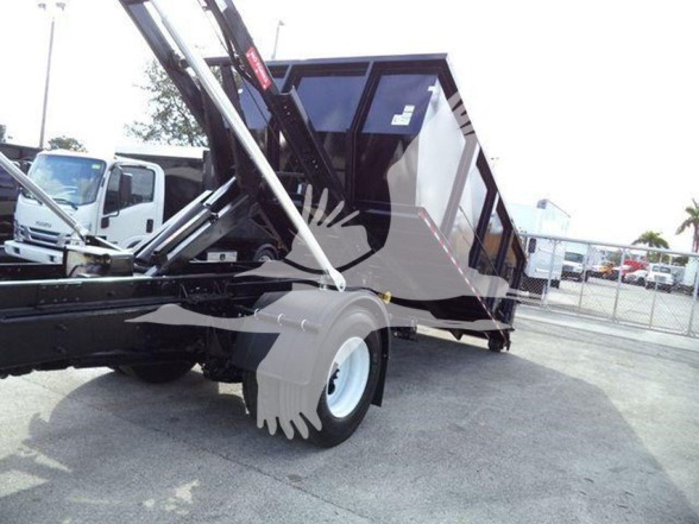Truck rear dump with hopper and hydraulic lifting arms in service bay showing International Durastar 4300 wheel and dump bed mechanism.