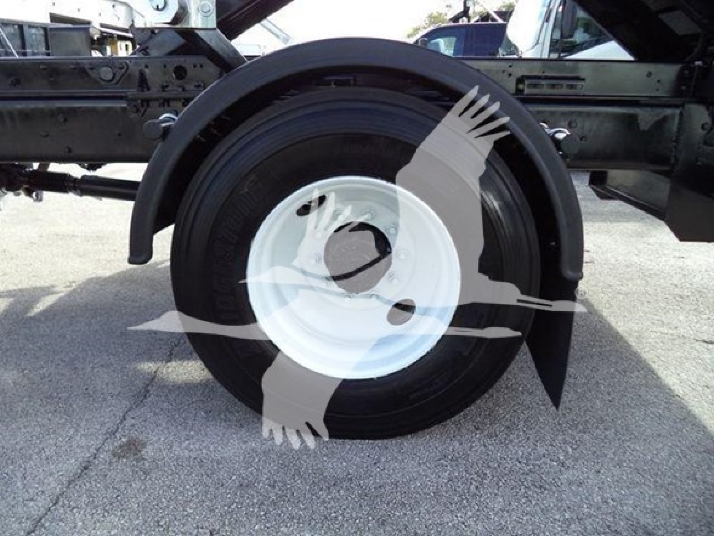Wheel and fender area of a 2019 International Durastar 4300 roll-off truck showing a white steel wheel and black tire mounted under the chassis.