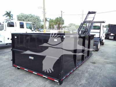 Container body showing black roll-off dumpster with ladder on rear, white painted eagle logo, and reflective red/white trim. Visible text includes no legible labels, though vehicle context and VIN present.