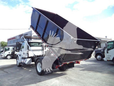 Truck-mounted dump bed on a 2019 International Durastar 4300 in a rolloff configuration with the hopper raised, showing rear and side view of the truck.
