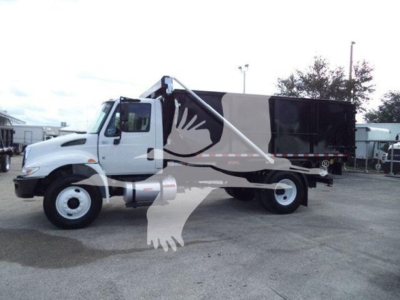 Truck side view showing a 2019 International Durastar 4300 roll-off with white cab and black dumping bed, VIN 1HTMMMML4KH515012, stock T15012.
