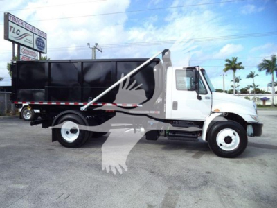 Truck side view of a white 2019 International Durastar 4300 roll-off truck with black dumping bed.