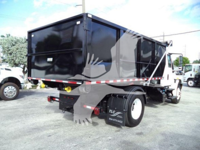 Dump truck in-service showing cargo dump bed and rear view with black cargo body, white cab, and dual rear wheels.