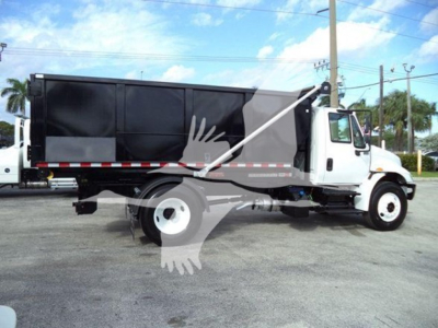 Truck side view showing a white cab and black dump body, with red/white reflective striping along the side and a hydraulic cylinder. No legible labels visible.
