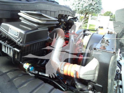 Engine bay of a 2019 International Durastar 4300 rollover truck showing radiator, air intake box, hoses, and wiring under the hood.