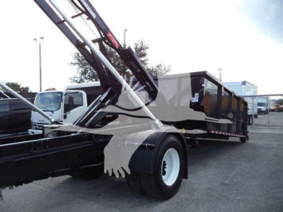 International Durastar 4300 roll-off truck in service with crane arm extended and a long black and gray dump body.