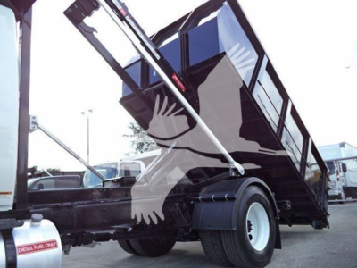 Truck dump/roll-off body in upright position showing hydraulic arms and fuel cap labeled diesel fuel only.