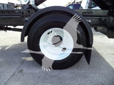 Wheel and fender area of a 2019 International Durastar 4300 roll-off truck showing a white steel wheel and black tire mounted under the chassis.