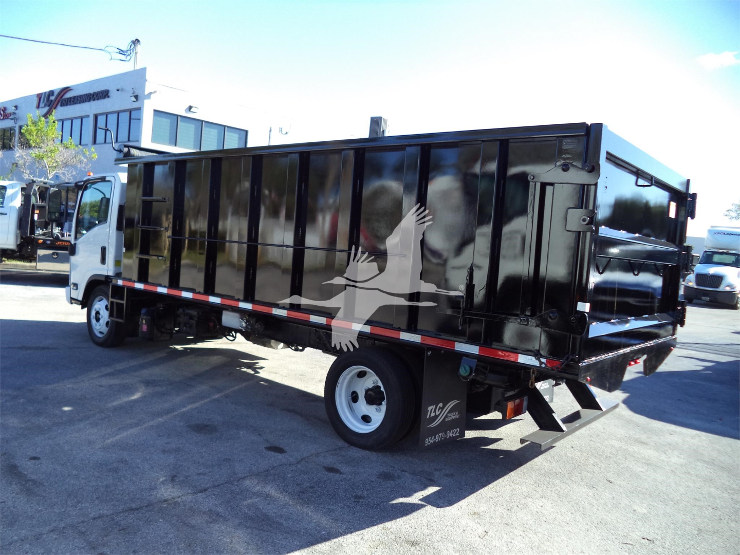 Isuzu NPRR dump truck with black dump body, side view showing rear and wheel, stock number 18FTDUMPNRRFM notations not visible.