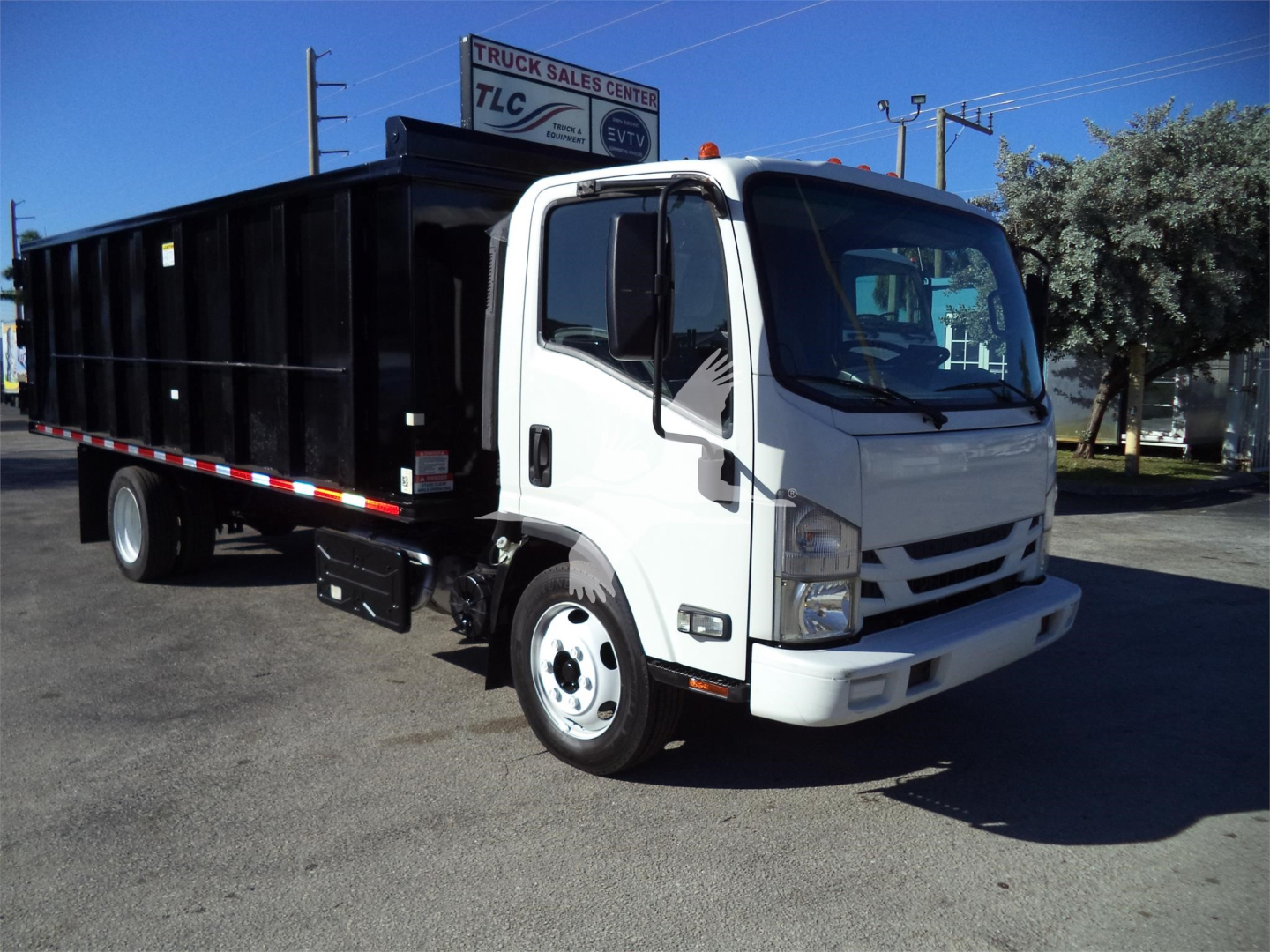 Isuzu NPRG Dump truck side view showing black dump bed and white cab.