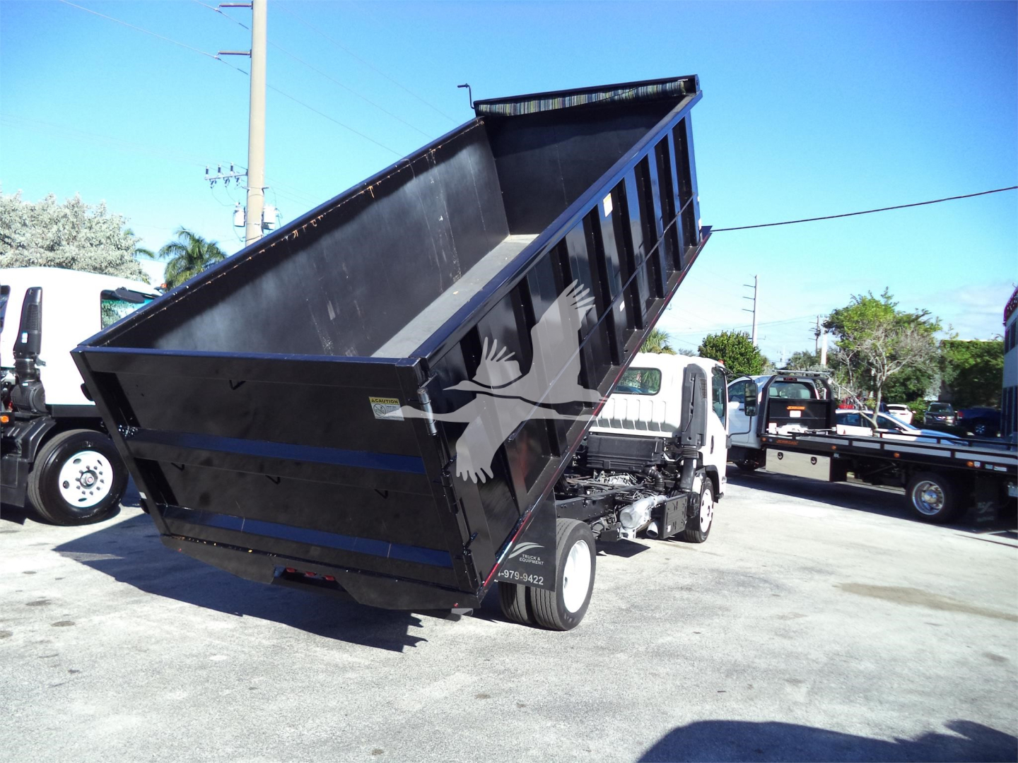 Isuzu NPRR dump truck in-service showing raised dump bed and rear wheels.