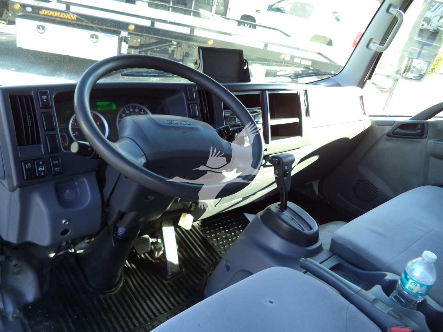 Isuzu NRR truck interior showing steering wheel, dashboard, and seating area with gear selector and cup on center console.