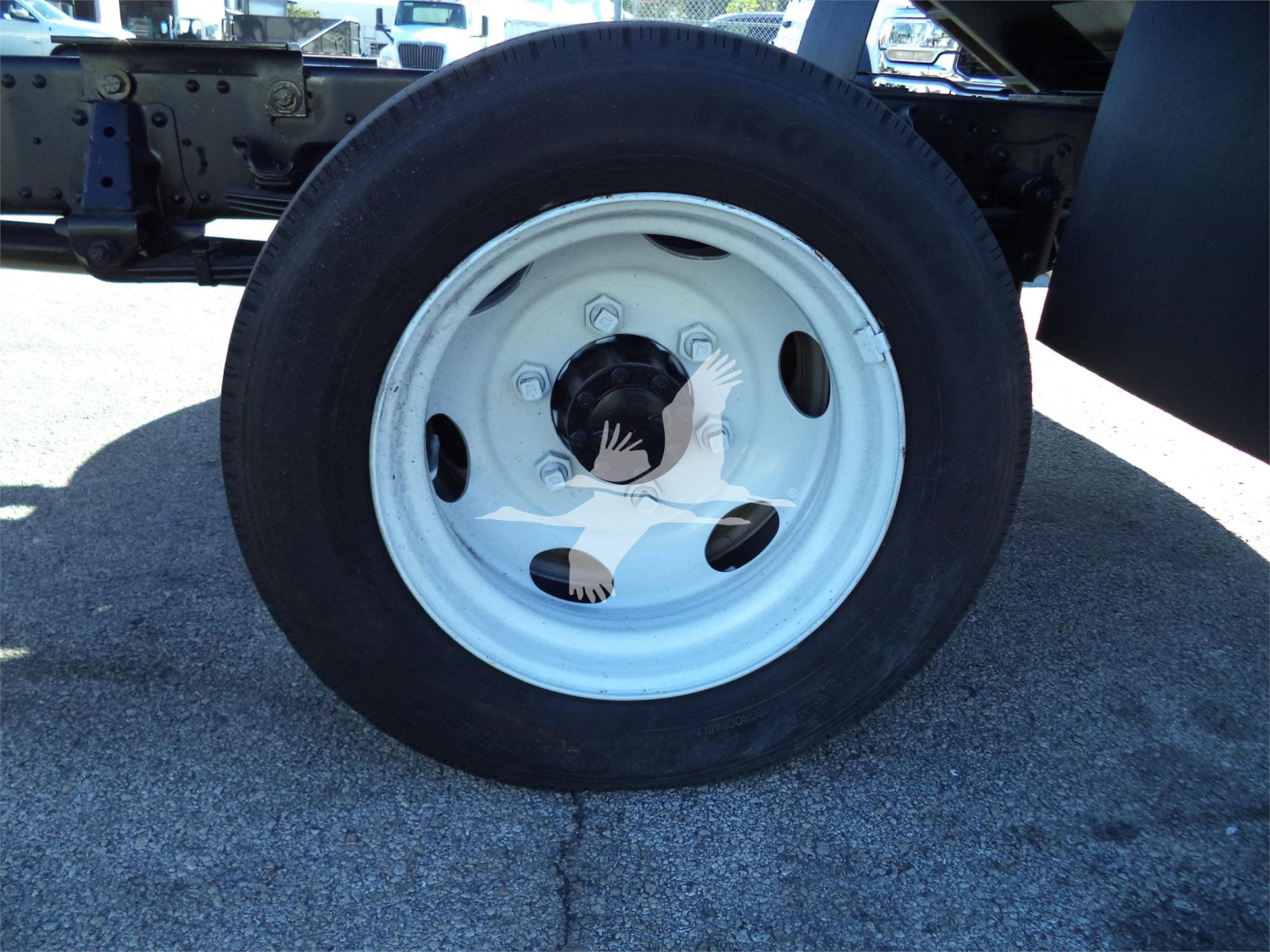 Isuzu NPRR truck wheel with white steel rim and black tire, undercarriage visible.
