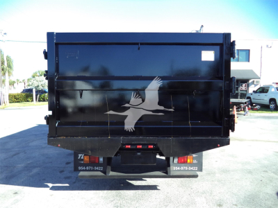 Back view of a black Isuzu dump truck bed with a white bird logo, in a parking lot.