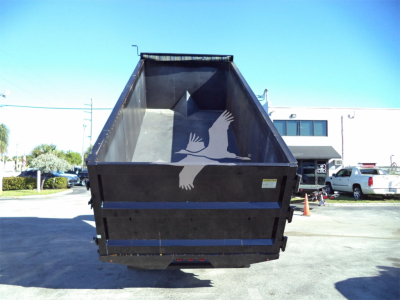 Dump truck bed of a Isuzu NRR dump truck with open tailgate, lot in background.