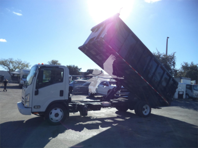 Isuzu NPRR dump truck in-service with raised dump bed showing hydraulic system and cab, side view.